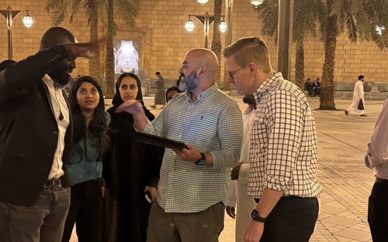 A team in a historic quarter at night, one holding the tablet, working out the next move