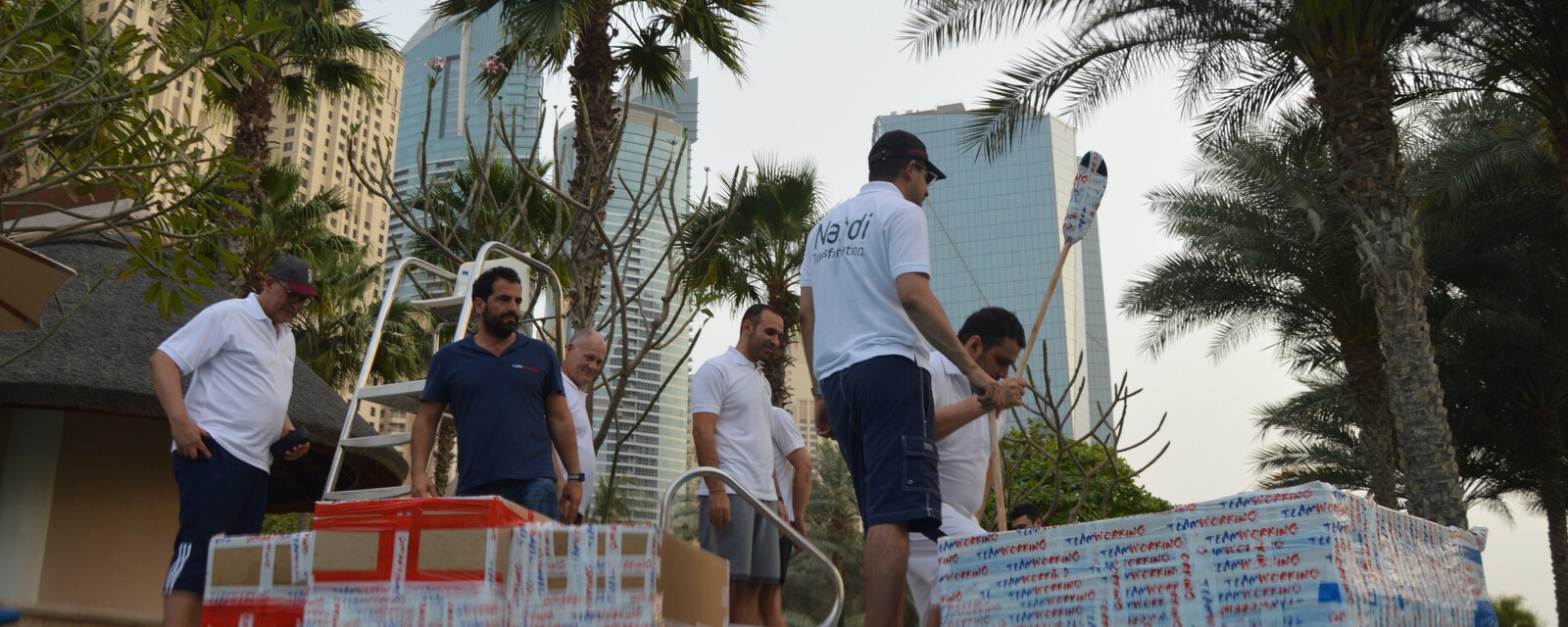 A team carrying cardboard boats, the Marina towers behind